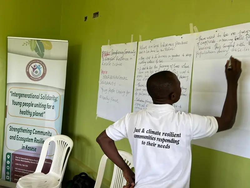 A participant writes on flip-chart paper in front of the Intergenerational Solidarity banner